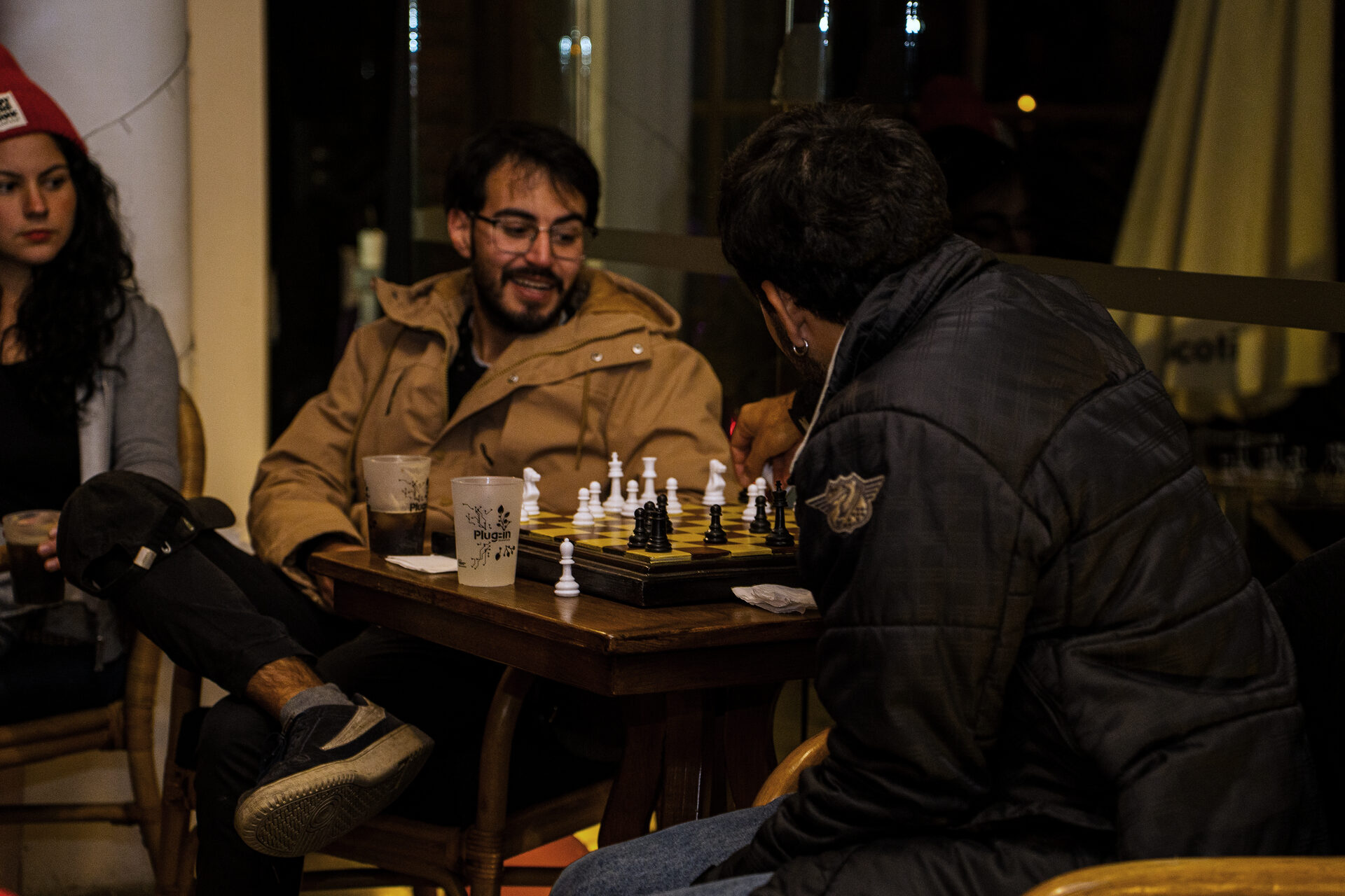 Dos asistentes juegan al ajedrez en una mesa de madera durante el encuentro.