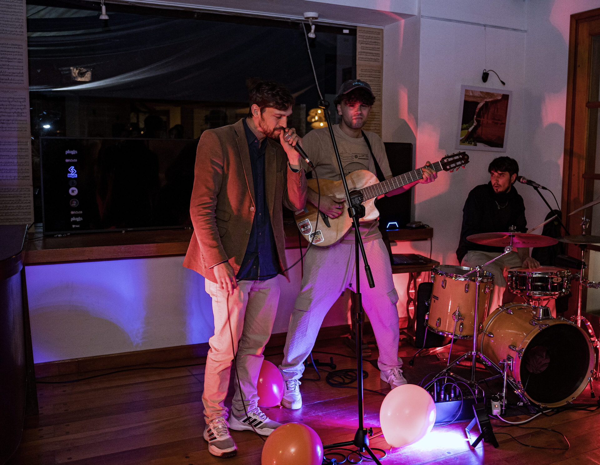 Banda en vivo con voz, guitarra y batería sobre el escenario.