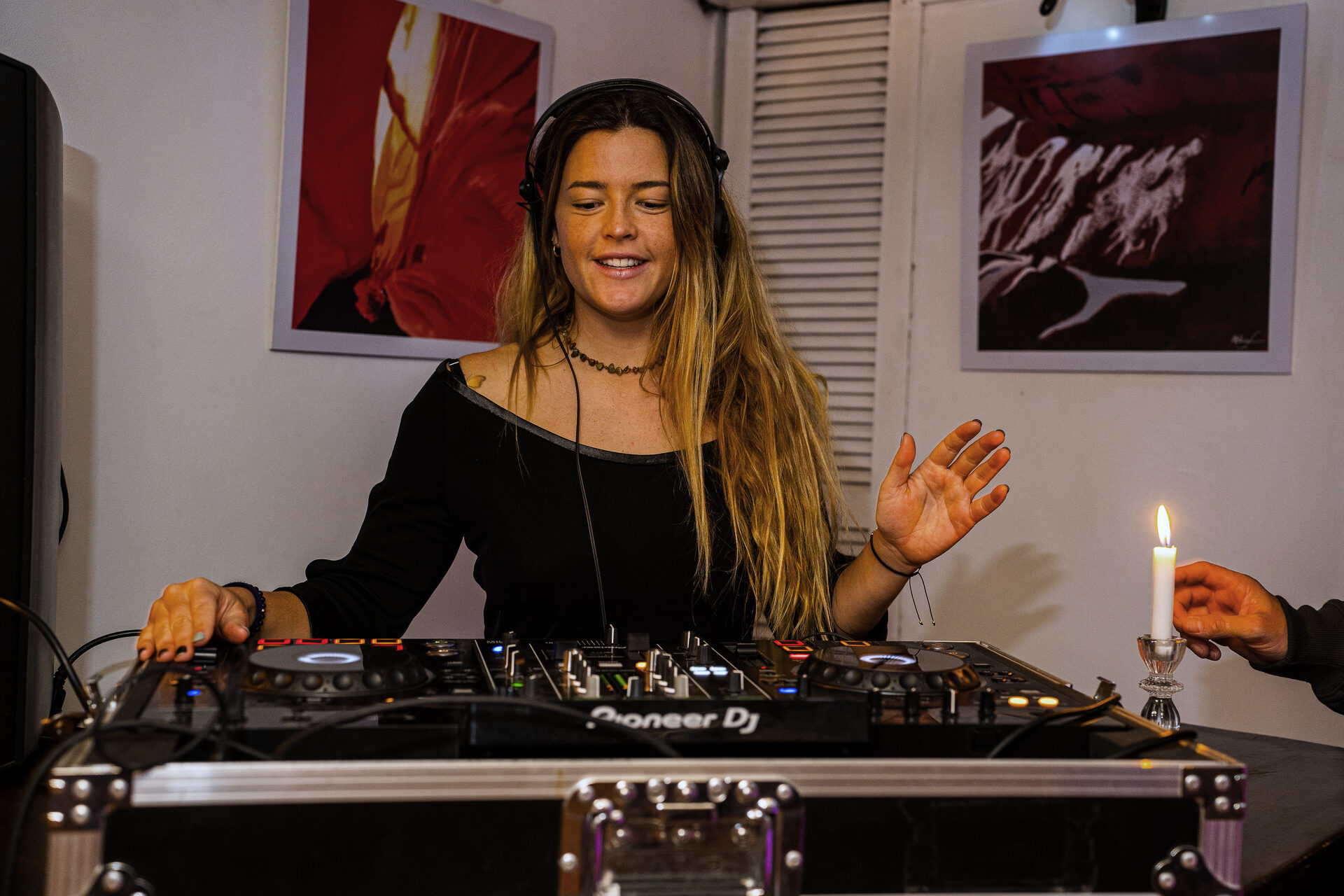DJ mezclando en la cabina junto a una vela encendida.