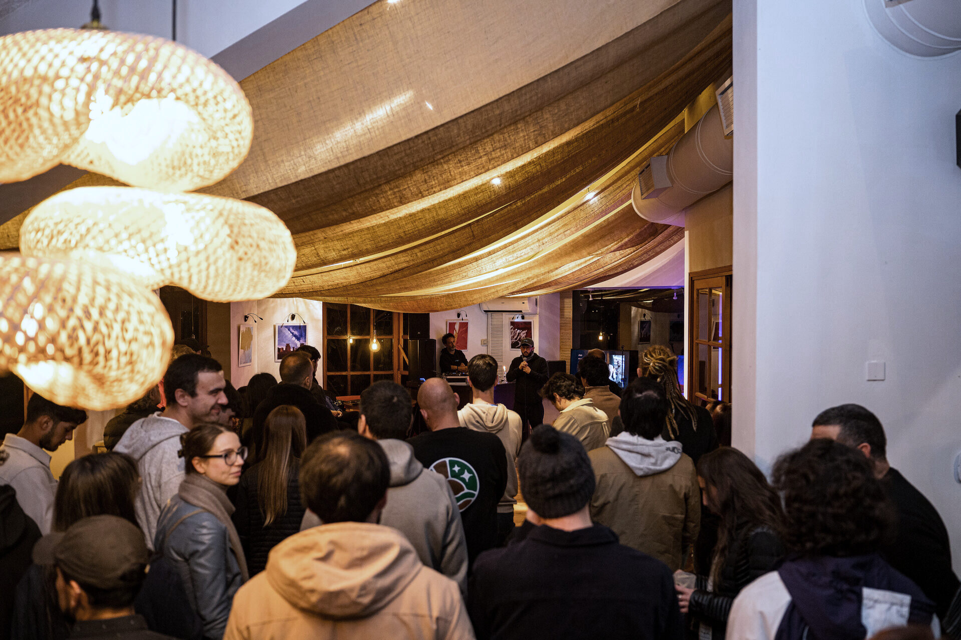 Público reunido bajo las lámparas de mimbre durante un encuentro.